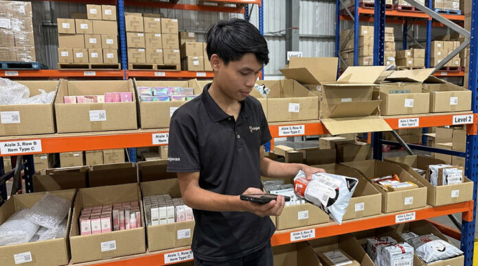 Ninja Van Malaysia warehouse staff using a Zebra handheld device to scan parcels on storage shelves